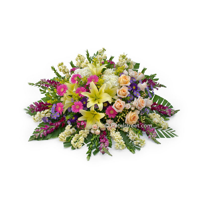 Bright mixed flower casket spray with Lilies, Daisies, Roses, Snapdragons, and accent flowers.
