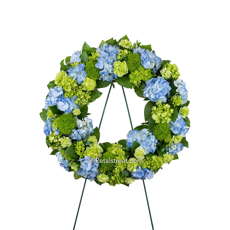 Beautiful funeral wreath with blue and green Hydrangea, Carnations, Green Trick, and mixed greenery.