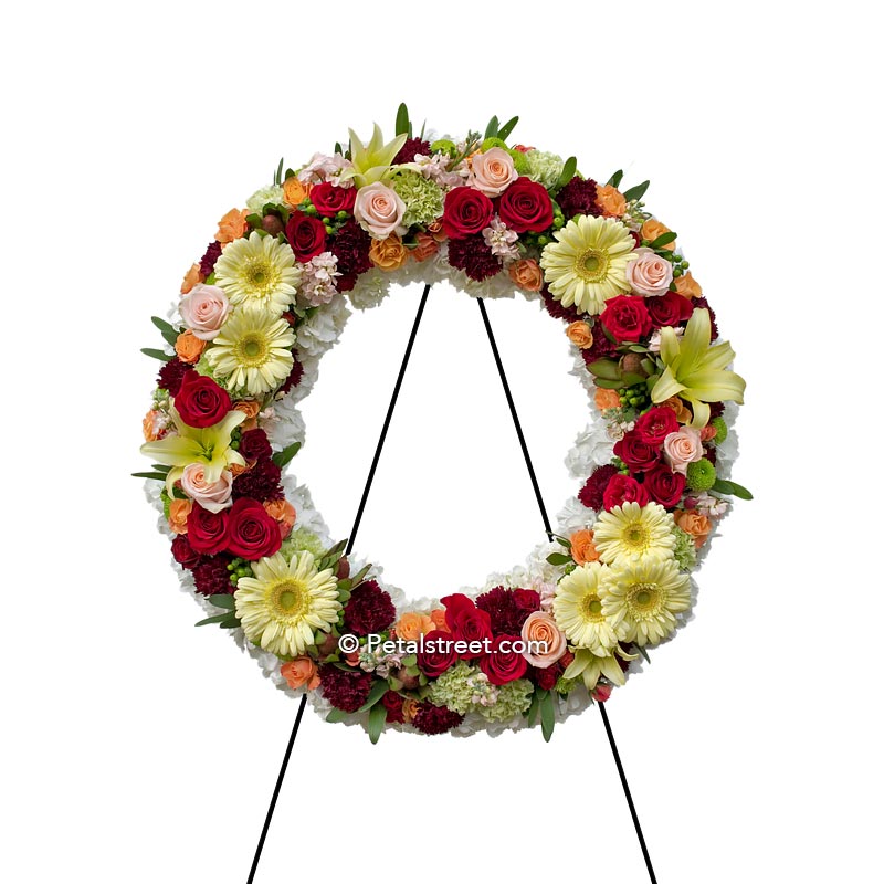 Funeral wreath with Roses, Daisies, and Carnations in bright colors.