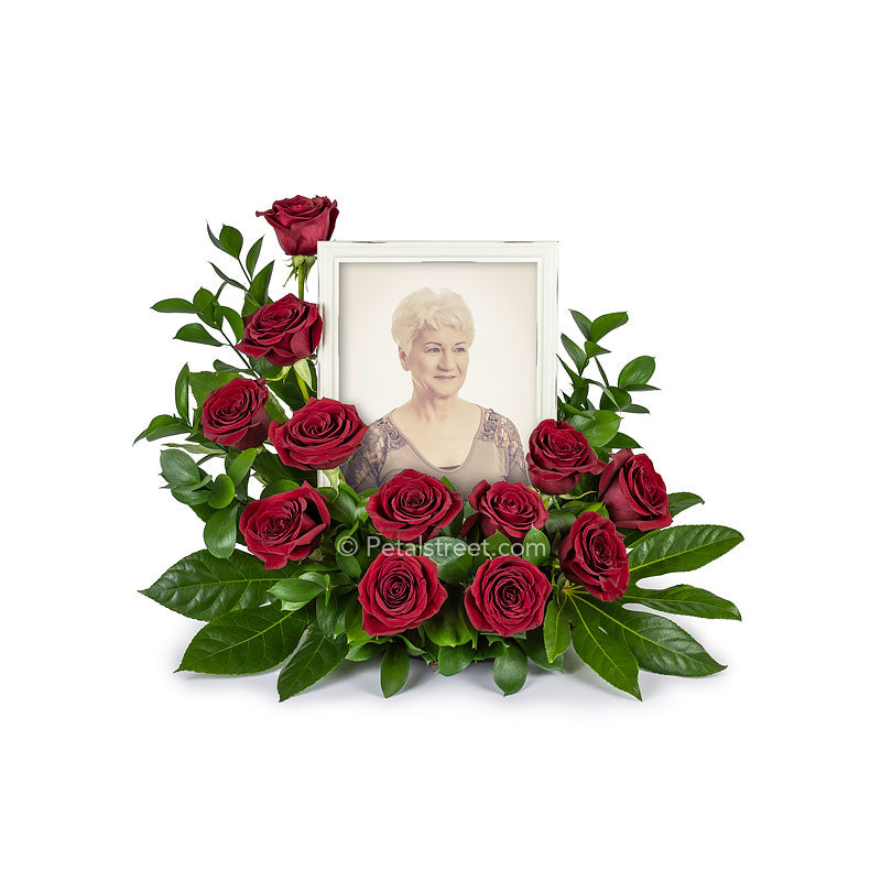 Cremation memorial floral arrangement with red Roses surrounding a photo frame of a loved one