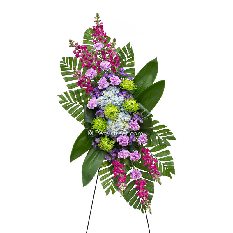 Funeral standing spray with pink, lavender, and blue mixed assortment of flowers by Petal Street Flower Company florist.