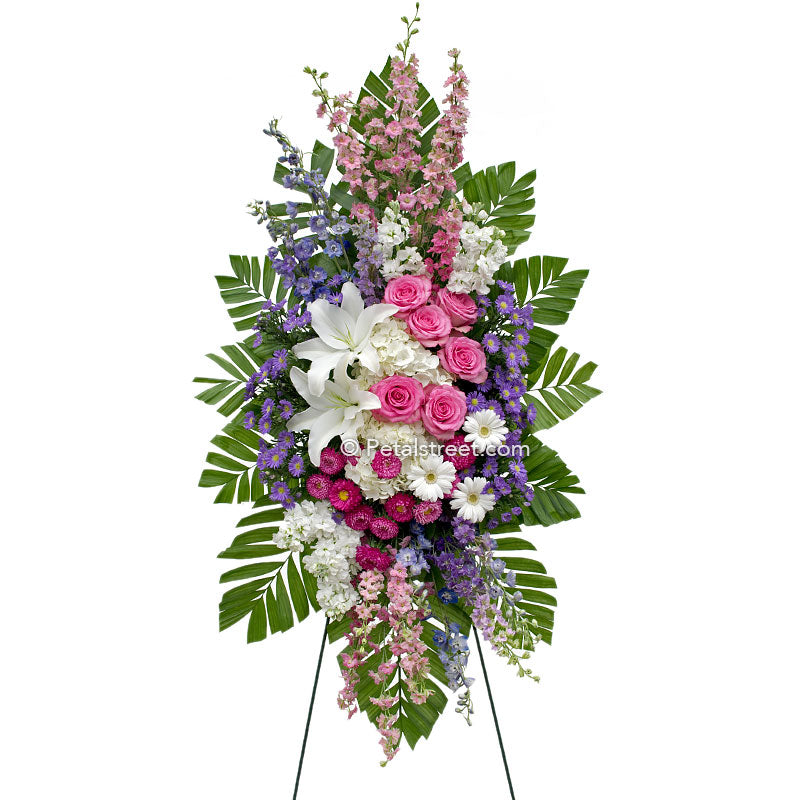 Standing spray with white Lilies and pink Roses, accent florals, lush Palm leaves.