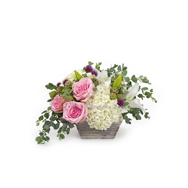 Pink Roses, white Hydrangea, and Eucalyptus arranged in a white washed box.