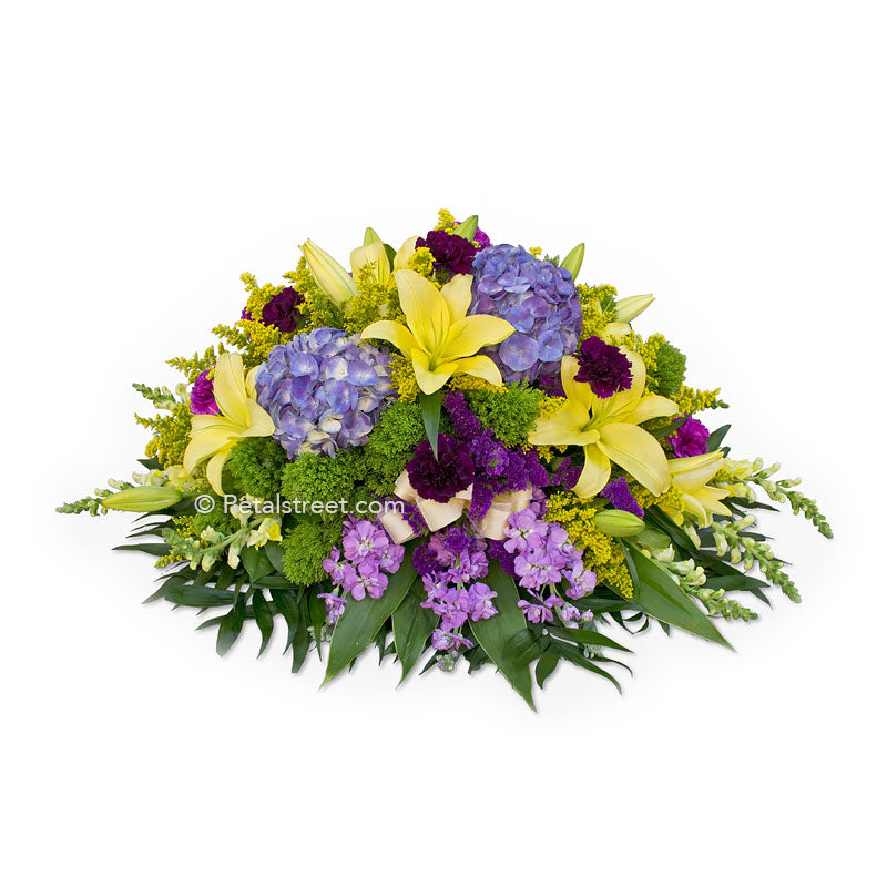 Yellow, purple, and green casket spray with Lilies, Hydrangea, Carnations, and accents flowers.