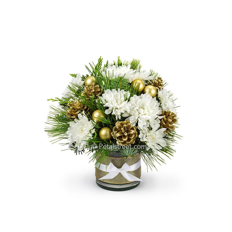 This little vase arrangement is simple and elegant with a touch of gilded glam, featuring bright white Mums arranged in mixed seasonal greens, gold painted Pine Cones, and gold holiday ornament accents.