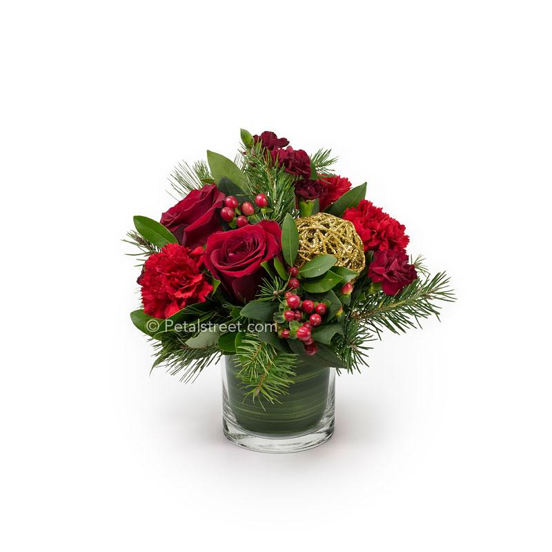 Christmas style flower arrangement with red Roses, Carnations, and Hypericum Berries arranged in seasonal greens.
