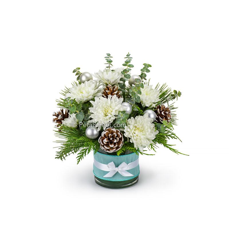 A blue, white and silver Christmas arrangement with white Mums, Eucalyptus, seasonal greens, frosted Pine Cones,  silver holiday ornament accents, and an aqua blue and white ribbon wrapped around the vase.