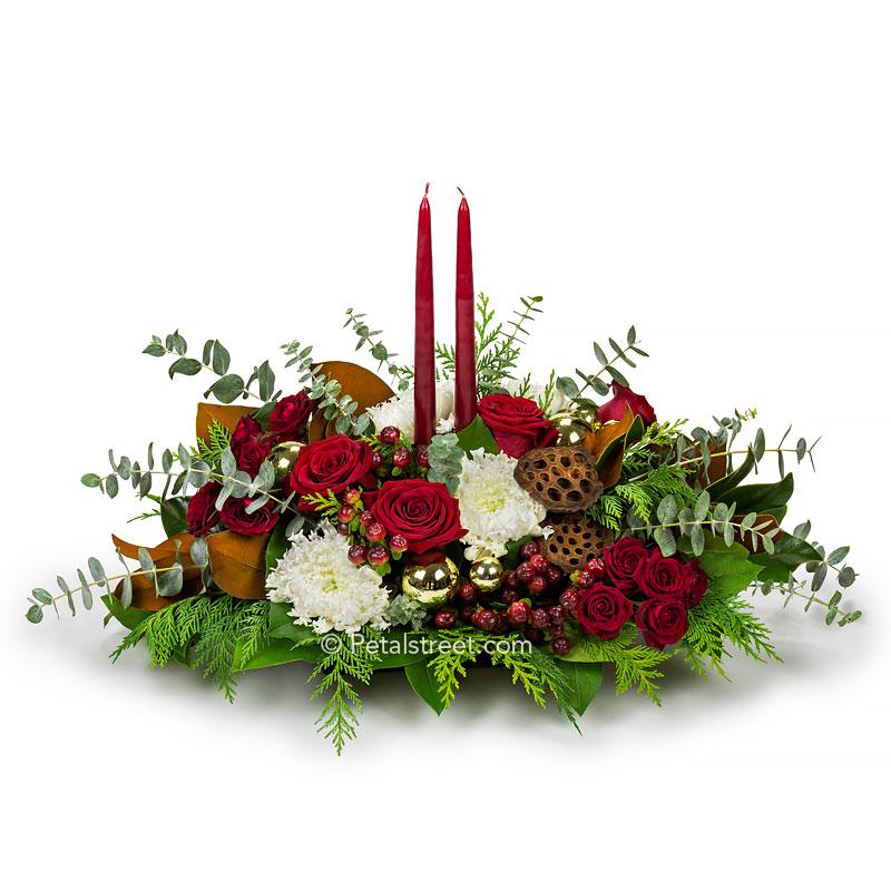 Red, green, and white Christmas table centerpiece with Mums, Roses, Magnolia Leaves, Eucalyptus, mixed seasonal greens, and two red candles.