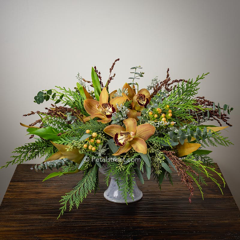 Elegant Autumn flower arrangement with light brown Cymbidium Orchids, Berries, Eucalyptus, and mixed foliage in a compote container.