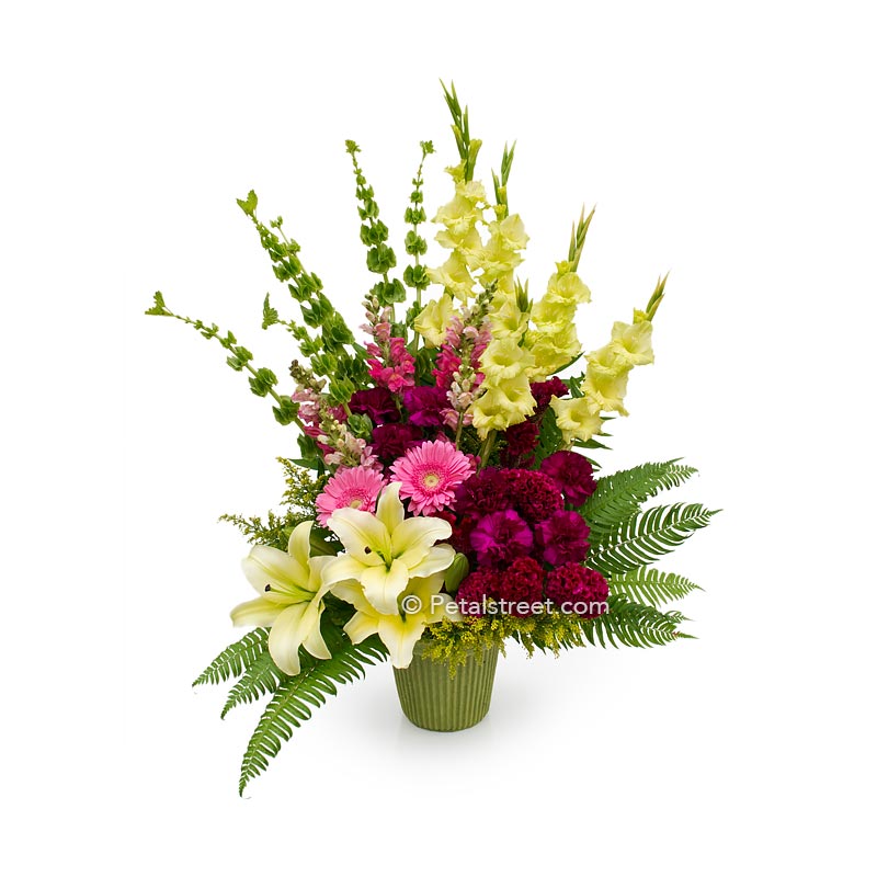 Beautiful funeral basket with pink Daisies, magenta Carnations, Snapdragons, and yellow Lilies and Gladiolas.