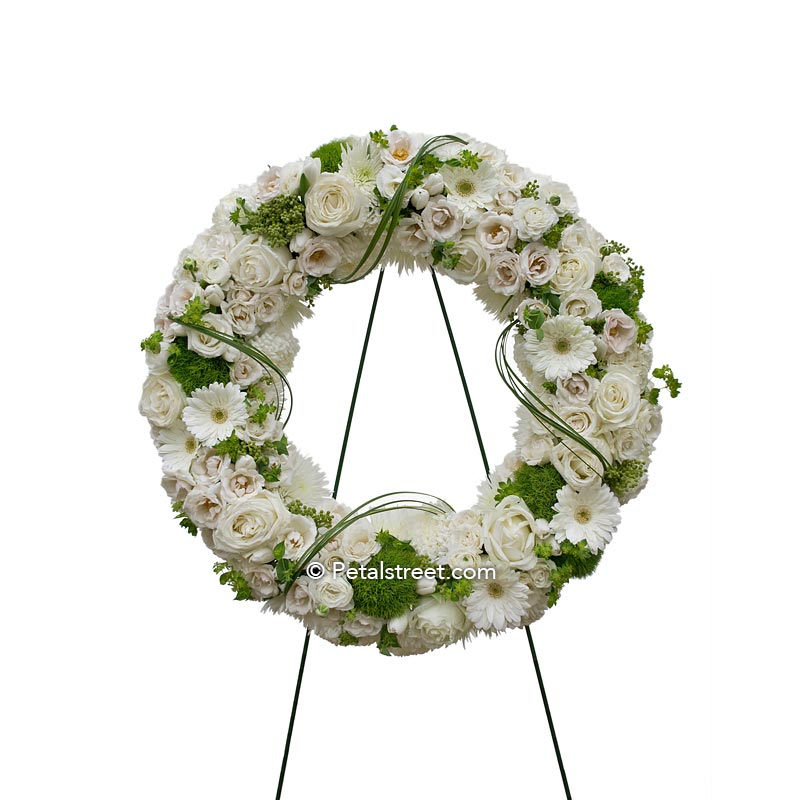 All white funeral wreath with a mix of flowers such Roses, Daisies, and Hydrangea.
