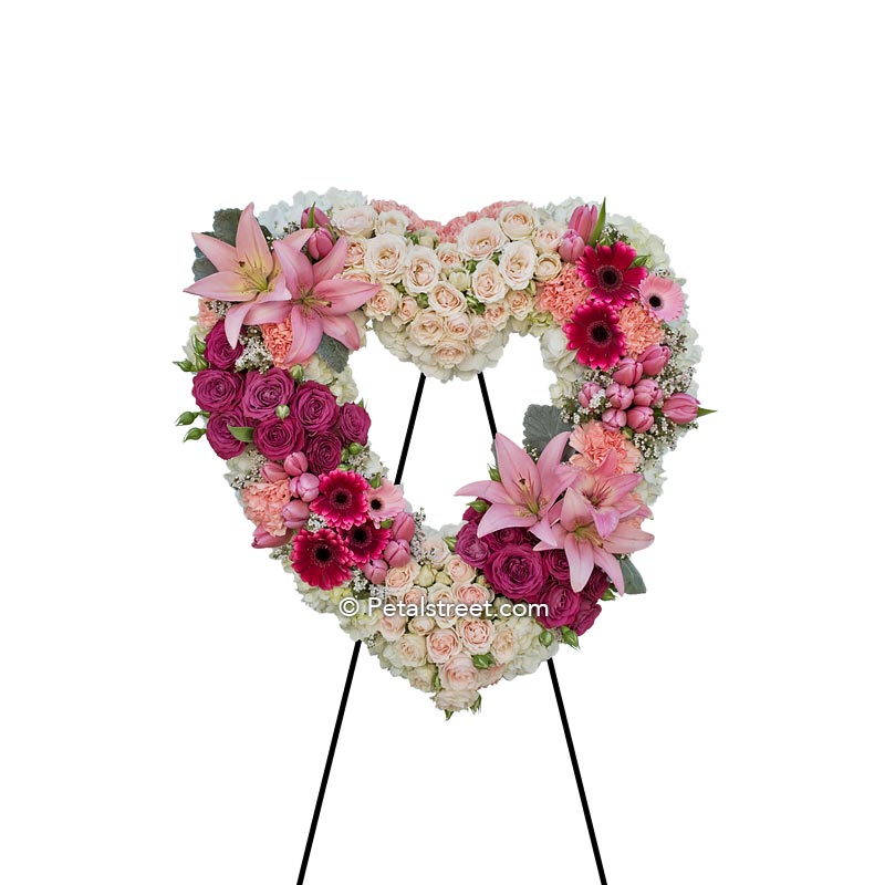 Funeral flowers heart form with pink Lilies, pink & white Roses, Carnations, Hydrangea, and accent foliage.