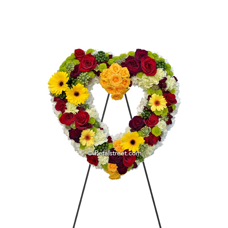 Colorful heart form with red & yellow Roses, yellow Daisies, white Hydrangea, green Button Mums, and Carnations.