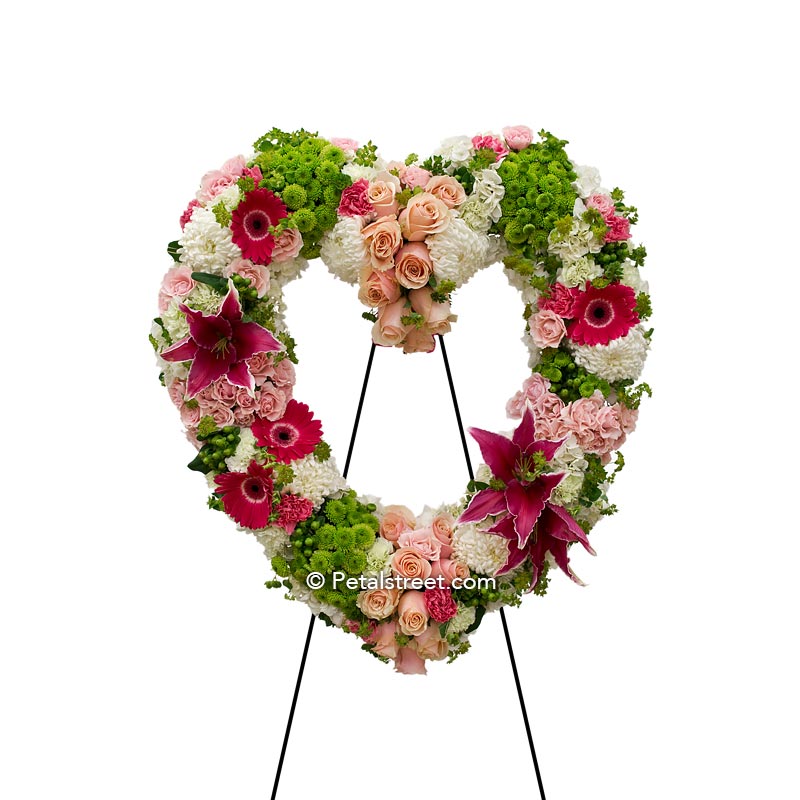 Funeral flower open heart form with pink Lilies, Roses, and Daisies accented with green Button Mums, Spider Mums, and Bupleurum.