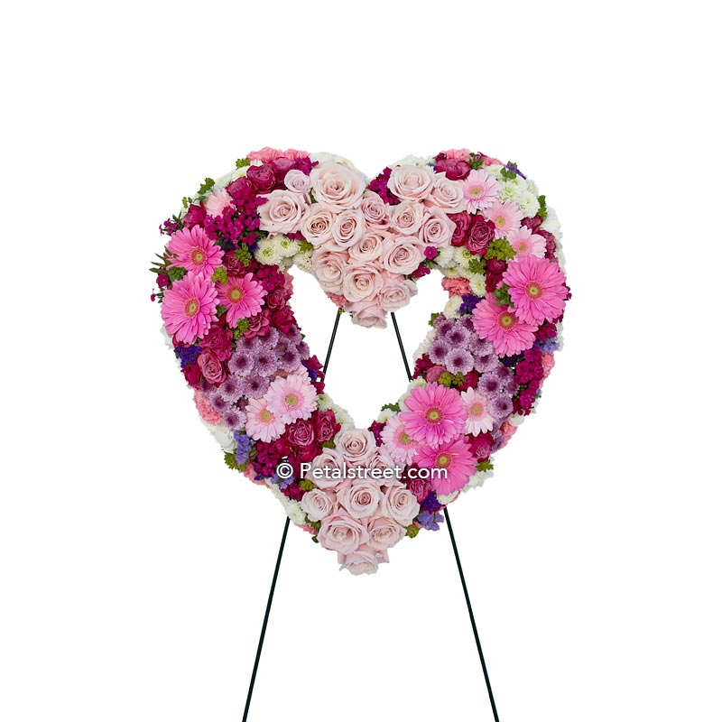 Pink, red, and burgundy heart form with Roses, Gerbera Daisies, Mums, Statice, and accent foliage.