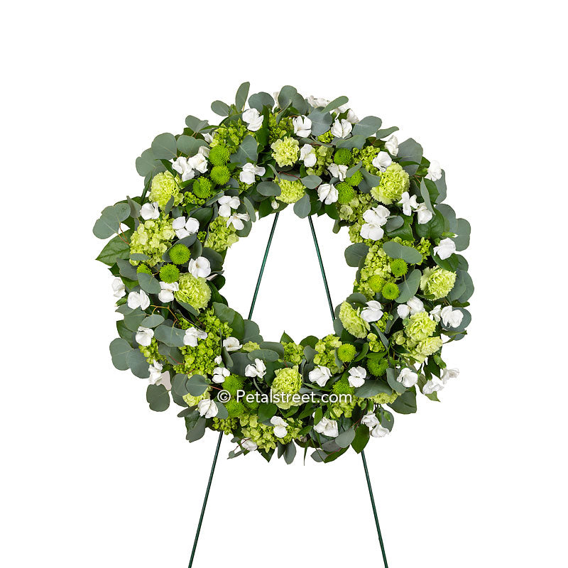Funeral wreath with white Dianthus softly mixed among a variety of green flowers such as mini Hydrangea, Carnations, and Button Mums, as well as Eucalyptus and mixed greenery.