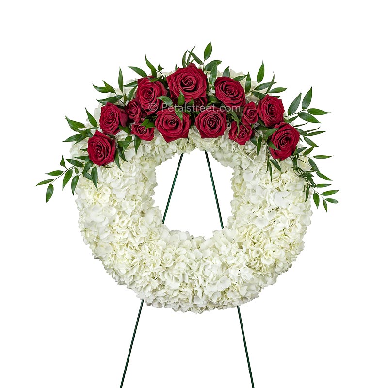Simple and elegant, this funeral wreath is arranged with red Roses, white Hydrangea, and accent foliage.