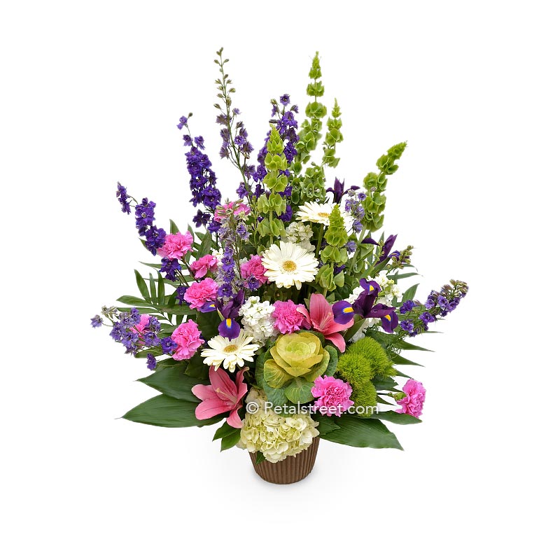 Garden style funeral basket with pink Lilies, white Daisies, Carnations, Larkspur, and Bells of Ireland.