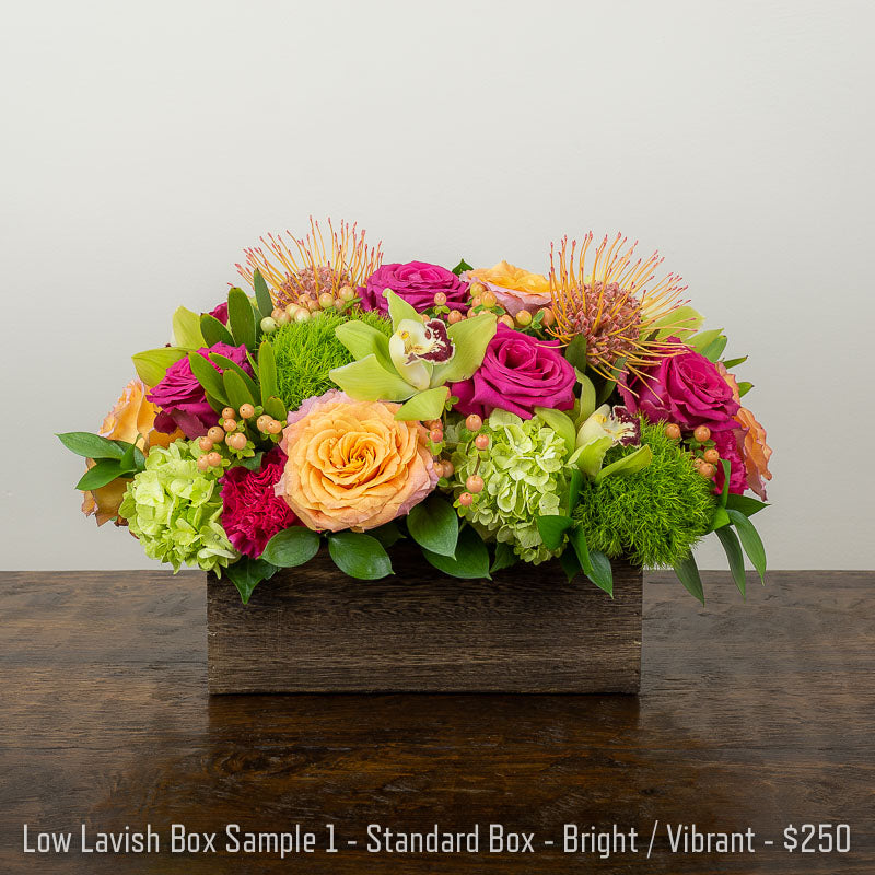 A bright and vibrant garden box arrangement  featuring Roses, Protea, Orchids, and Hydrangea in a wood box container