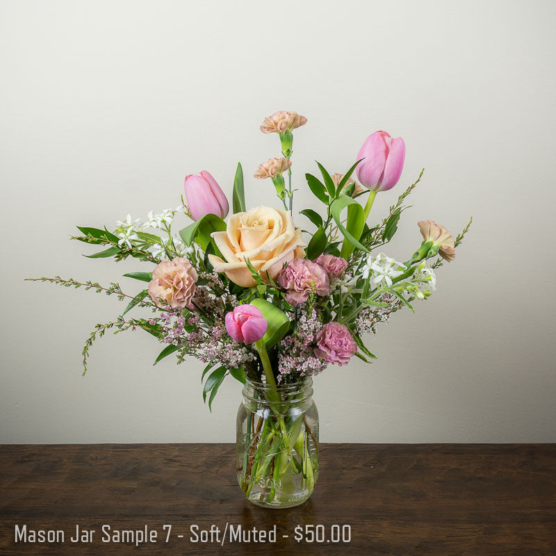 Small mason jar of flowers in soft pastel colors with Roses, mini Carnations, Tulips, and accent blooms and foliage