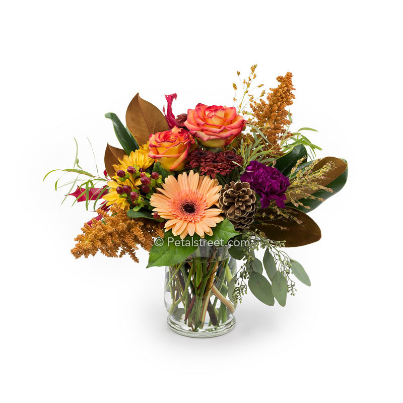 Orange Roses, Gerbera Daisies, Mums, red Berries, and Pine Cone Accents arranged in a vase.