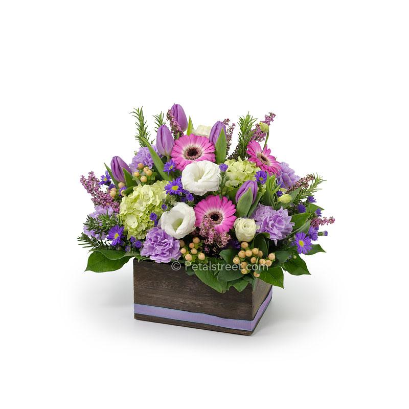 Vibrant flower mix with mini Gerbera Daisies, Tulips, mini Hydrangea, Carnations, Berries, and assorted accents arranged in a wood box.