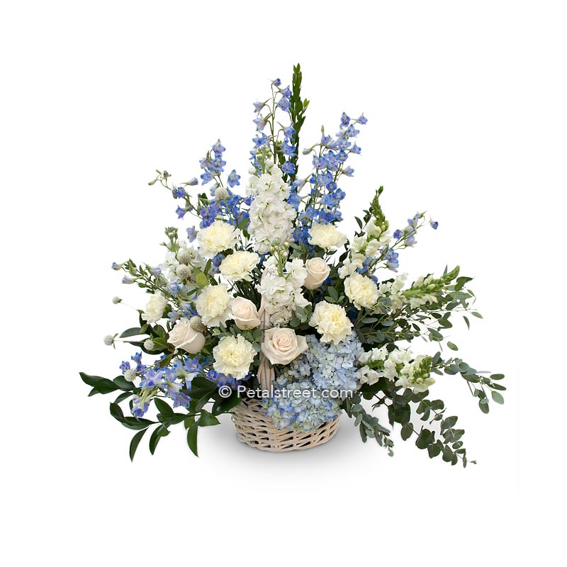 Sympathy basket of white Roses, Carnations, blue Hydrangea, blue Delphinium, Eucalyptus, and accent greenery.