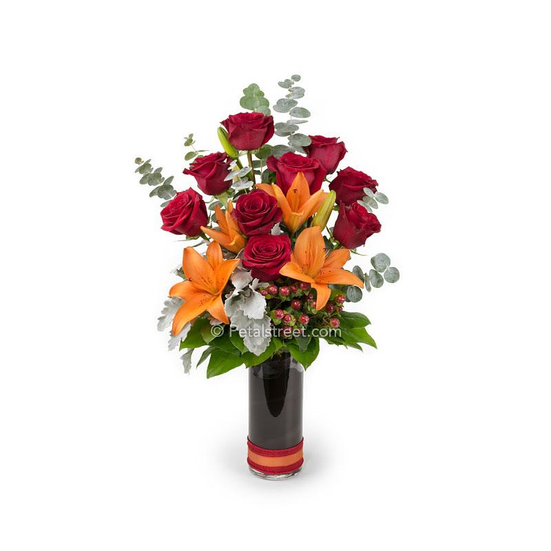 Tall flower vase arrangement for Valentine's Day with red Roses, orange Lilies, Hypericum Berries, Dusty Miller, and Eucalyptus.