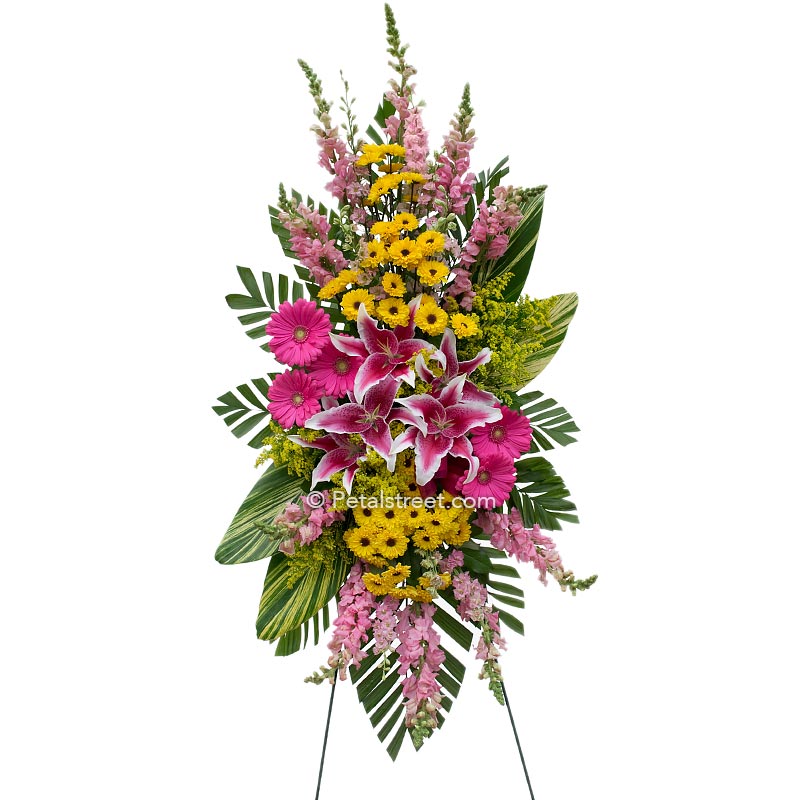 Beautiful pink Lilies and bright yellow Asters arranged in a funeral standing spray.
